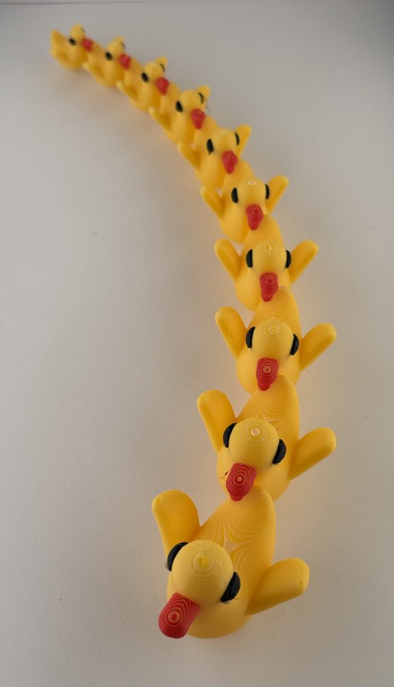 A curving line of yellow 3D printed ducks