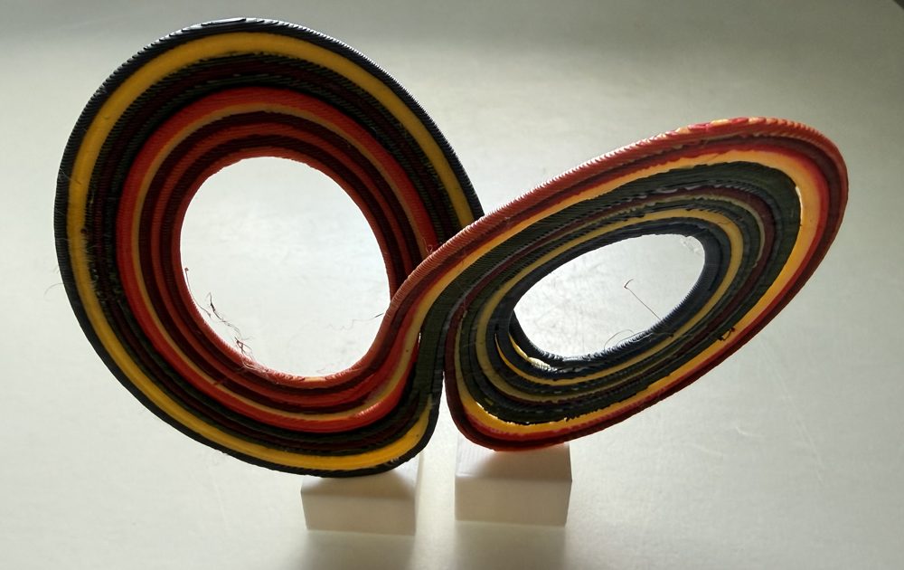 3D printed object of two joined loops in layered black, red and yellow plastic