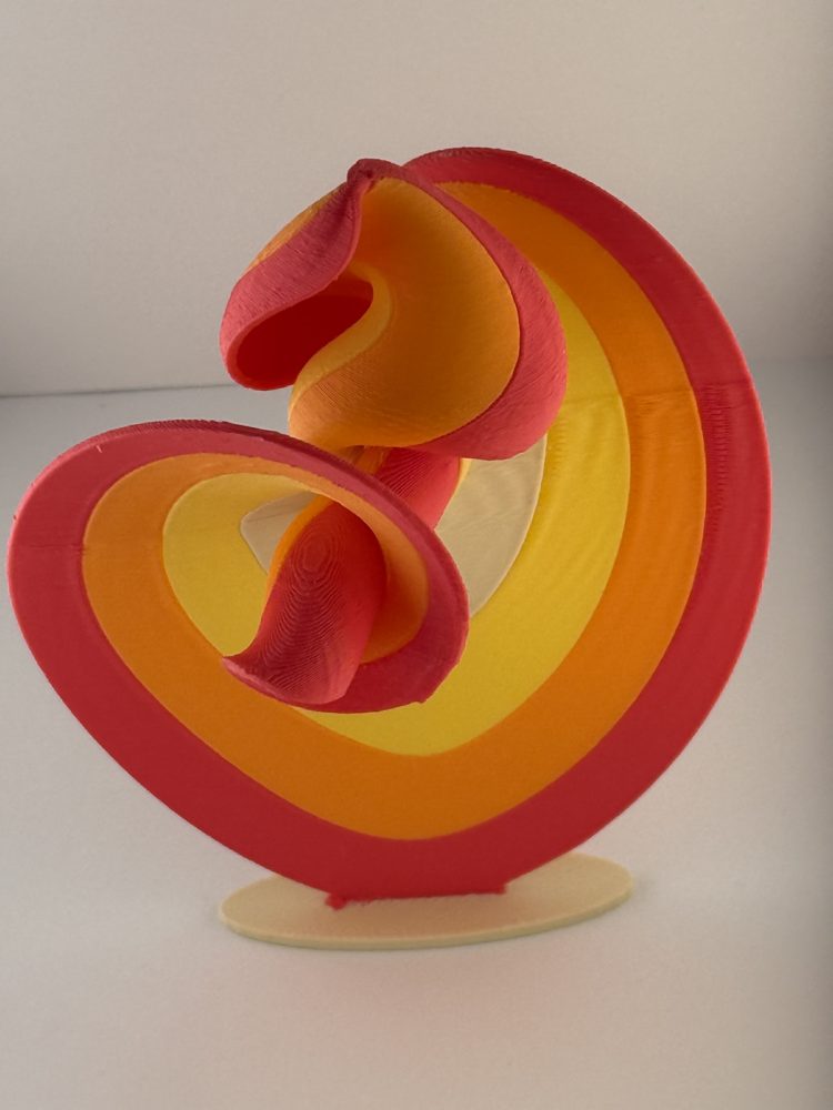 3D printed sculpture of curving red, orange and yellow bands on a stand